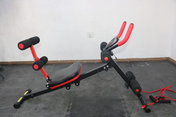 A black and red ab trainer machine with a padded backrest, adjustable seat, and multiple roller pads. The machine is designed for abdominal and back workouts.