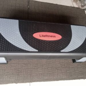 A gray and black aerobic step board with a textured surface. The board has a rectangular shape with rounded corners and four non-slip feet. The word "Litefitness" is printed on the top of the board in red.