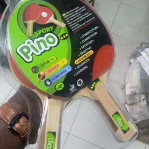 A pair of red and black table tennis paddles in a plastic blister pack. The paddles have wooden handles and rubber surfaces. The packaging includes the brand name "Pino" and information about the product's specifications and recommended age.