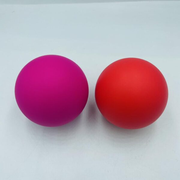 Two silicone massage balls, one pink and one red, placed side by side on a white background.