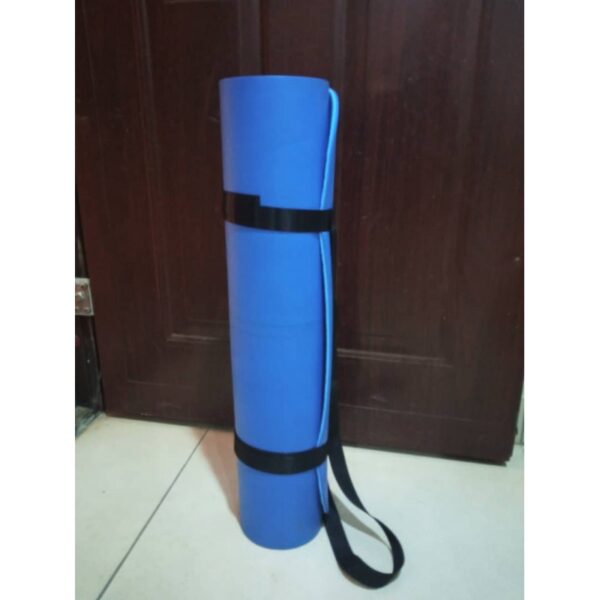 A blue yoga mat rolled up with a black strap around it. The mat is leaning against a door in a room.