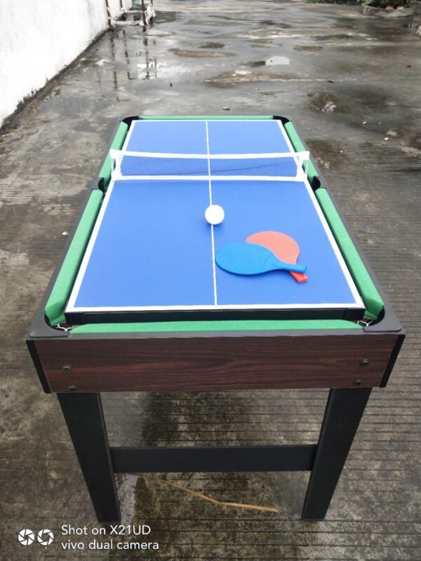 A multi-game table with a blue table tennis surface, a net, and a red paddle. The table also has a green surface underneath, likely for another game like pool.